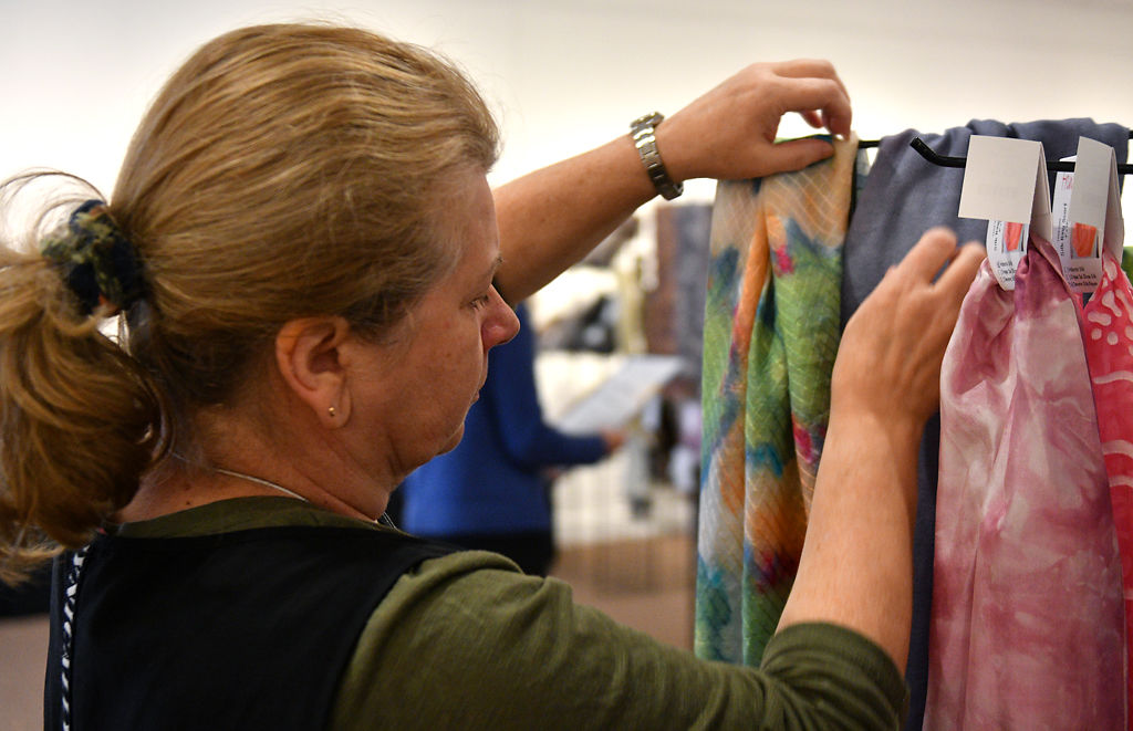 Kate Shipova adjusts scarves on a rack during setup